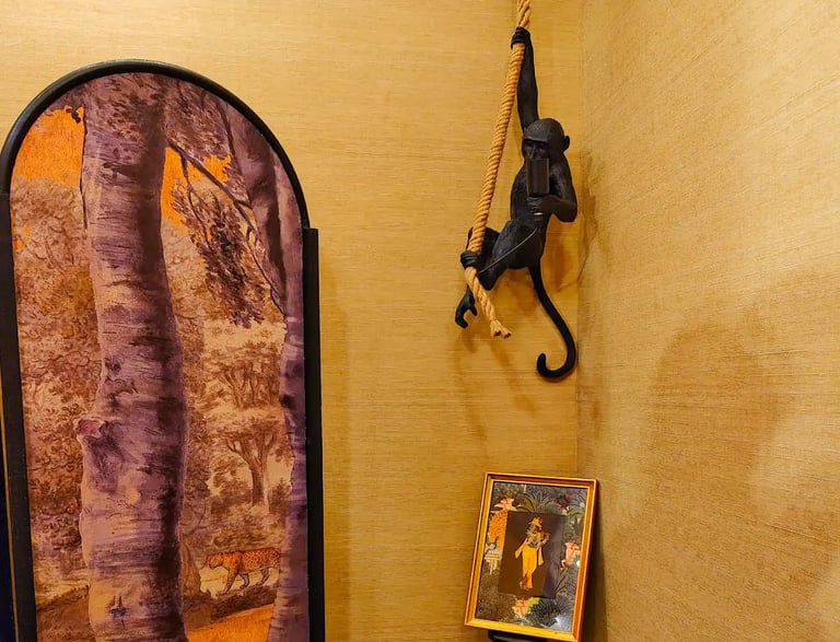 Black monkey hanging lamp with rope in a room featuring jungle themed wall art and decor.