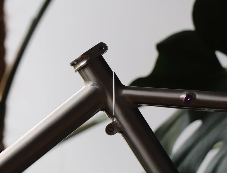 Close-up of a custom titanium bicycle frame showing the seat post clamp and precision welding details.