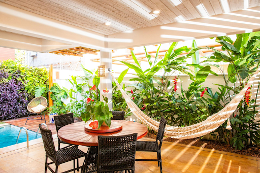 table and chairs in bright room with tropical plants, a hammock, and a pool