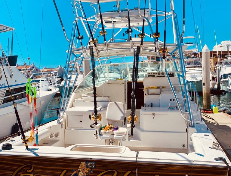 A deep sea fishing boat named Good Hooker docked in a marina with several fishing rods and reels.