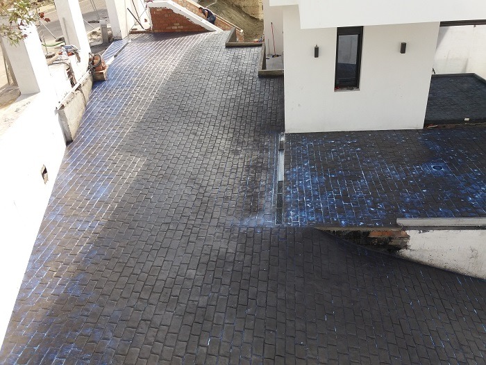 Superficie de hormigón impreso en color pizarra con diseño de adoquines, ideal para entradas y caminos residenciales modernos