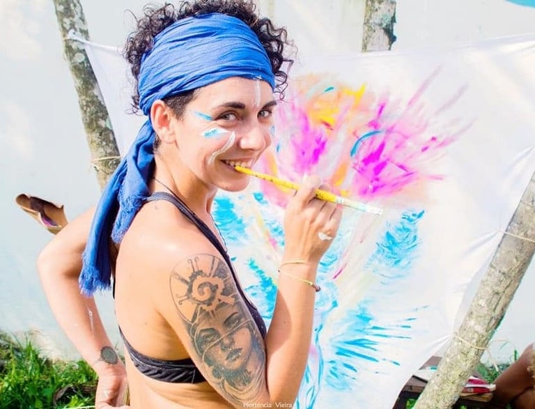 Naía souriante avec un pinceau, et une toile en cours de live painting
