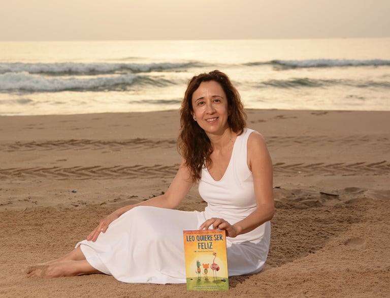 Foto de la autora de Leo wants to be happy con el primer libro de Leo en la playa