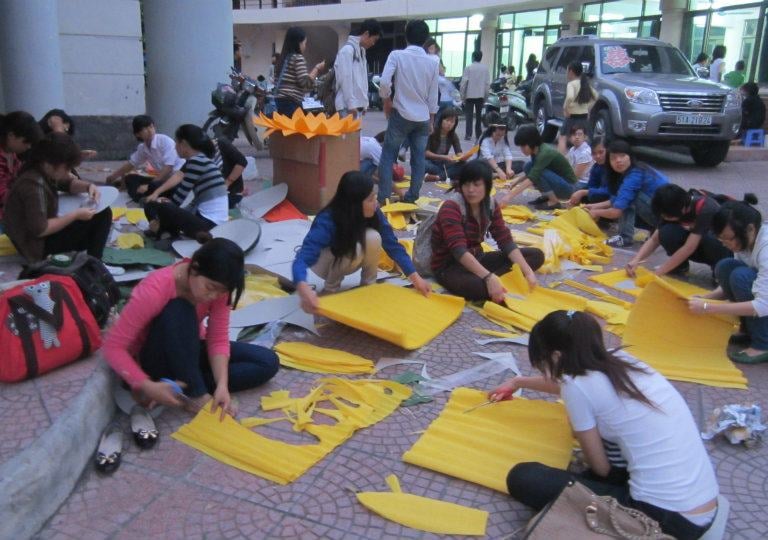 a group of people sitting on the ground with yellow paper