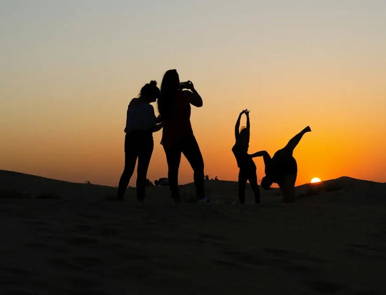 A group of people doing yoga in the desert, silhouetted against the setting sun