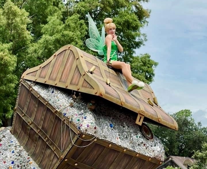 Tinkerbell sitting on top a treasure chest during a parade