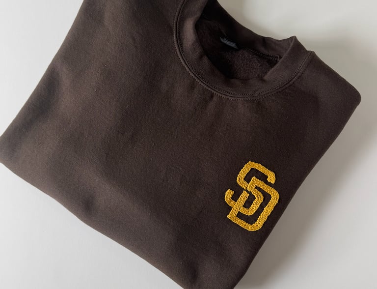 `a brown San Diego Padres sweatshirt with the SD logo embroidered in golden yellow