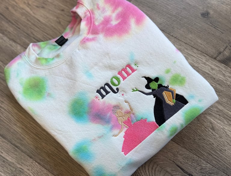 a white, pink and green tie dyed sweatshirt with the word "mom" embroidered on it