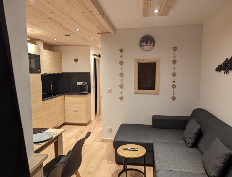 Open living space inside a warm Val Thorens ski apartment with lounge area, dining table and modern mountain kitchen