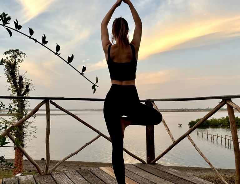 Pose de yoga avec vue sur le bolong et le début de la mangrove depuis le boutique hôtel Maison Fimela situé au coeur du Sine 