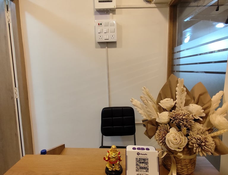 Office reception desk with flower arrangement, Buddha statue, and PhonePe QR code payment scanner.