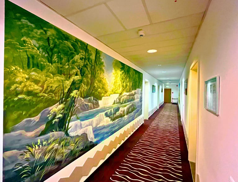 A long hallway with a large nature mural of a waterfall and green forest on the wall.
