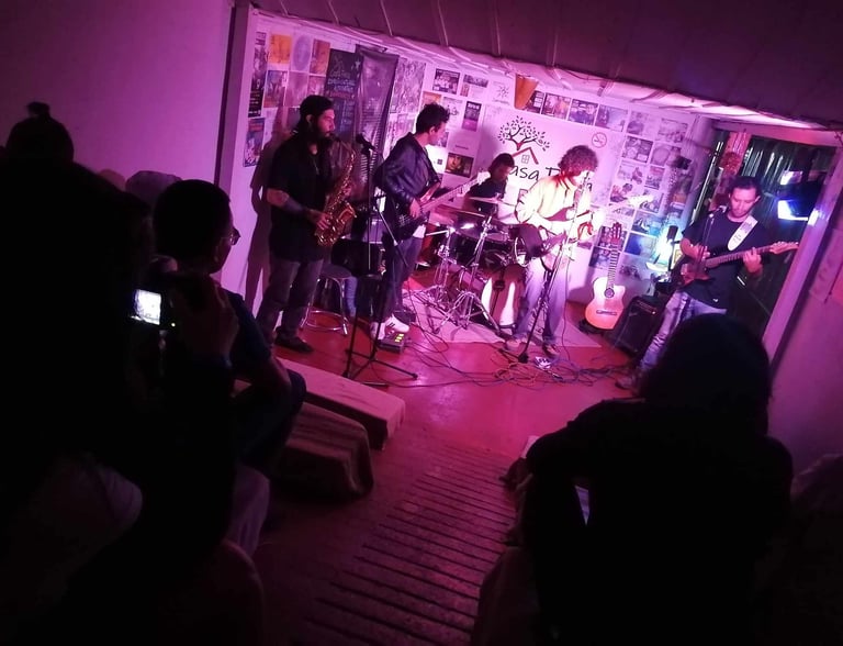 Banda en vivo interpretando jazz fusión en un escenario pequeño con iluminación púrpura y el público