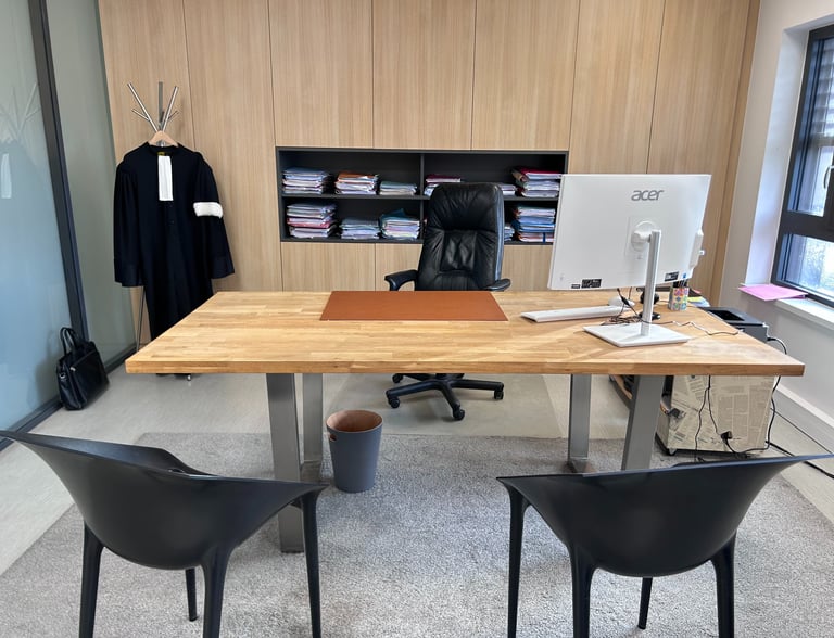 Modern lawyer office with a wooden desk, black leather chair, and a legal robe hanging in the background.
