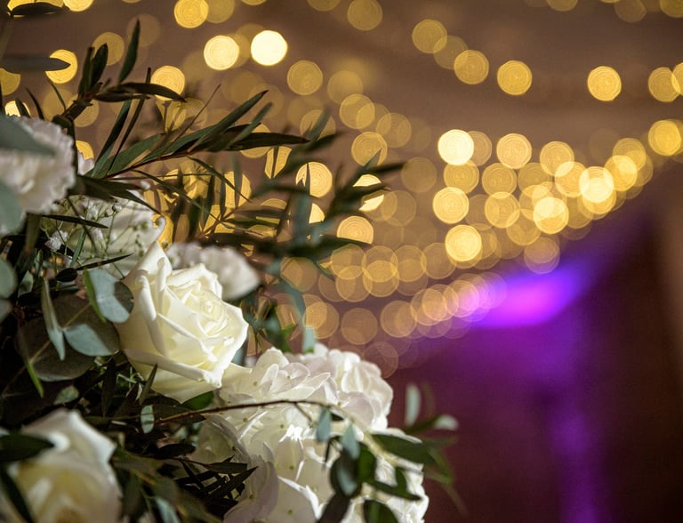 a bunch of white roses in a vase with lights