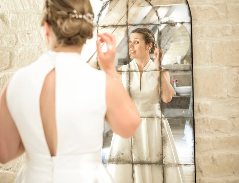 a woman in a white dress is looking at herself in the mirror