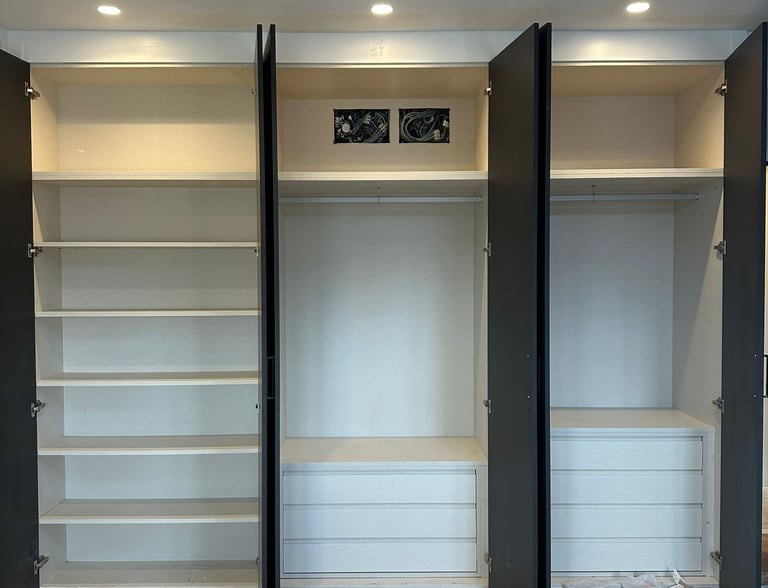 Armario abierto, tres secciones, estantes, cajones, barras.