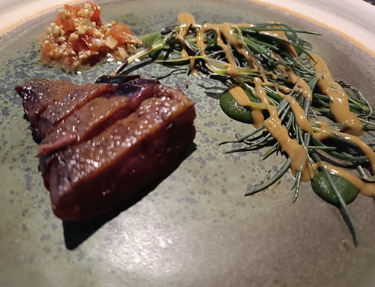 Dettaglio di una portata del Grow Restaurant con carne, erbe aromatiche e salsa vegetale