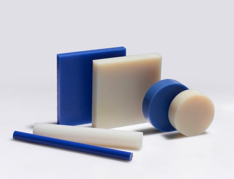 Assorted blue and white industrial plastic sheets, rods, and discs for engineering fabrication.