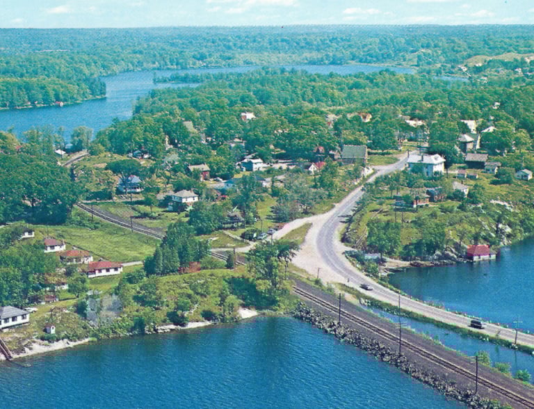 Aerial view of Thousand Islands landscape with lush islands, blue river water, and coastal roads.