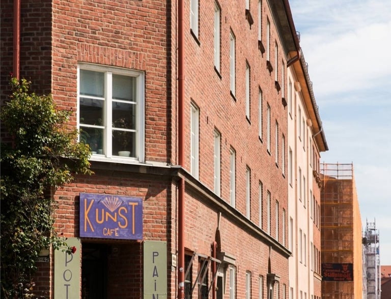 "Kunst Cafe" exterior with brick walls, signs, and outdoor tables.