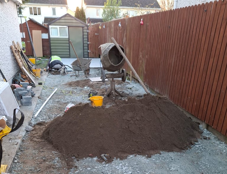 a pile of dirt in a backyard with a concrete wall