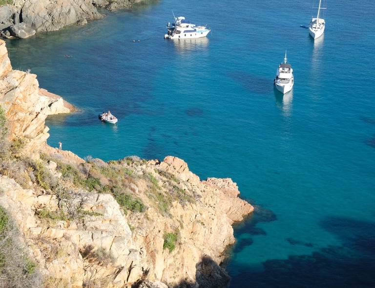 a group of boats in the water near a cliff