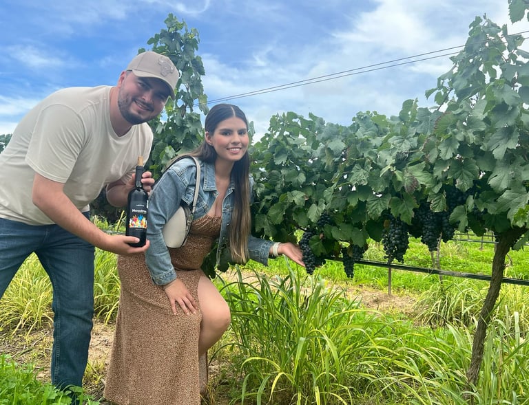 Pareja en un viñedo tomando fotos con las uvas