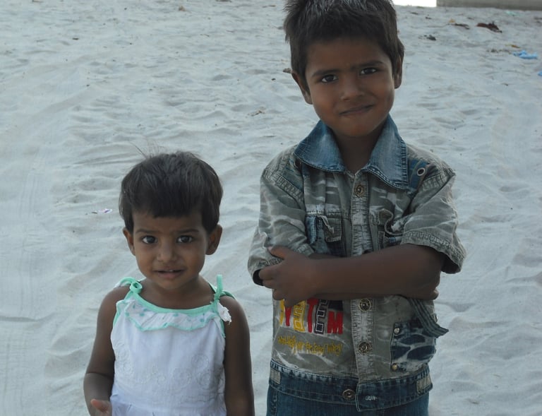 two young children standing in the sand