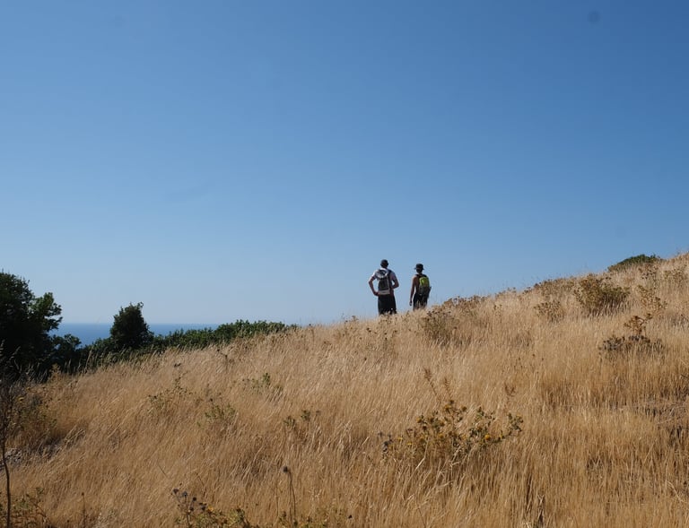 two people walking on a hill with a blue sky in the background