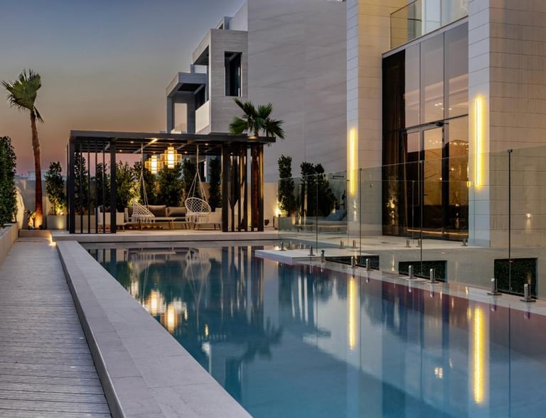 Outdoor poolside lounge area with hanging chairs and greenery at sunset.