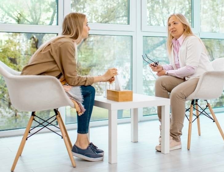 two women sitting at a table with a cup of coffee