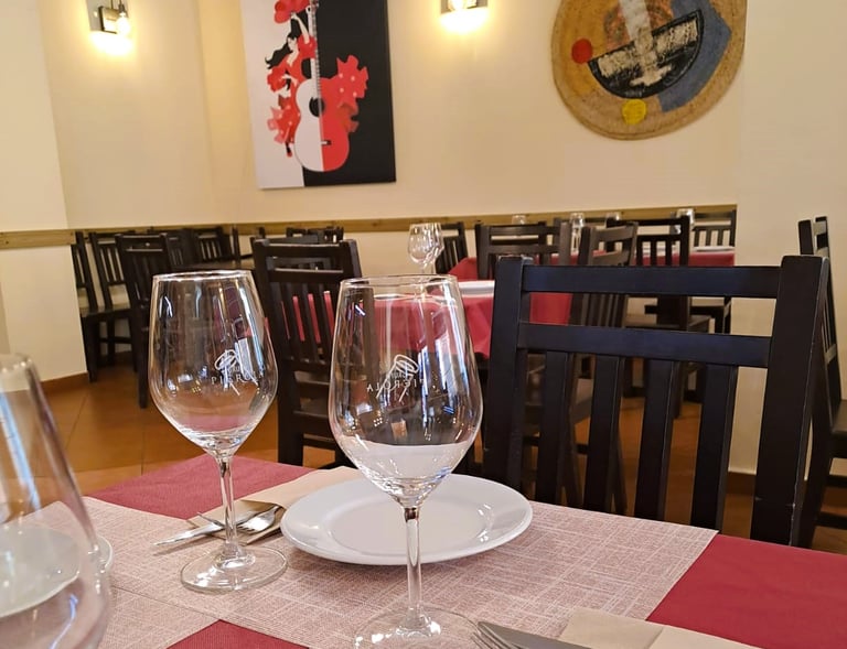 Interior que representa la Historia del Bar Las Tinajas Huelva, con mesas preparadas y un cuadro decorativo al fondo.