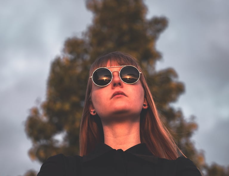 a women in a black jacket and sunglasses staring into the sunset