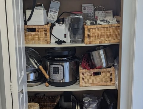 Kitchenware closet with bowed melamine shelving and disorganized clutter