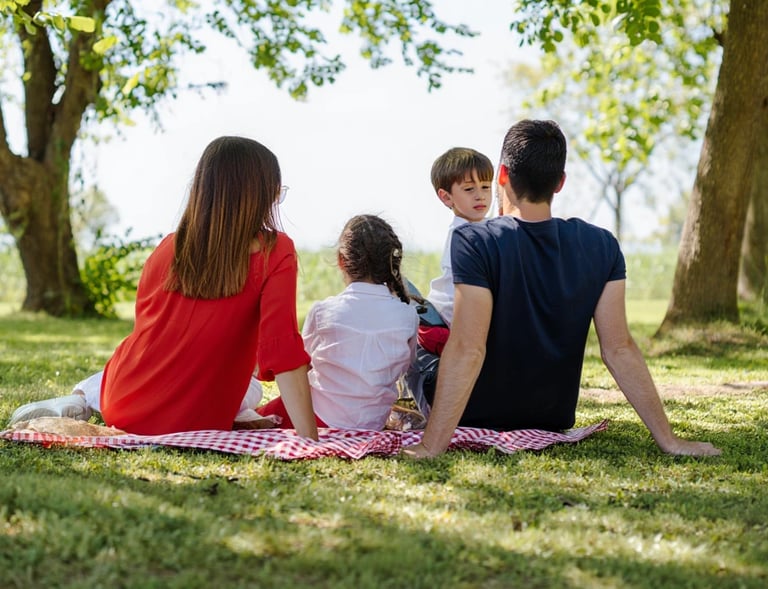 Eine Familie mit zwei Kindern sitzt beim Picknick.