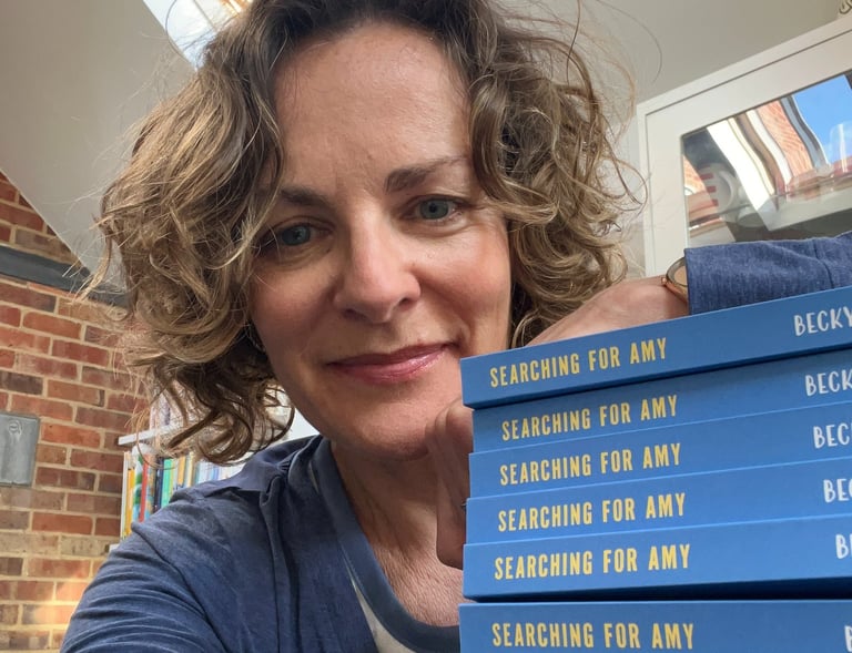 author with a pile of copies of Searching for Amy