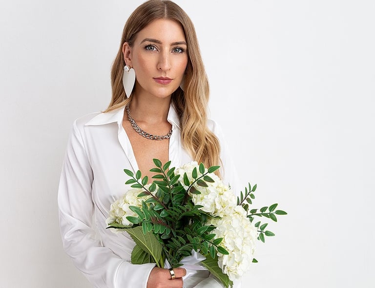 a woman in a white shirt and a necklace with flowers