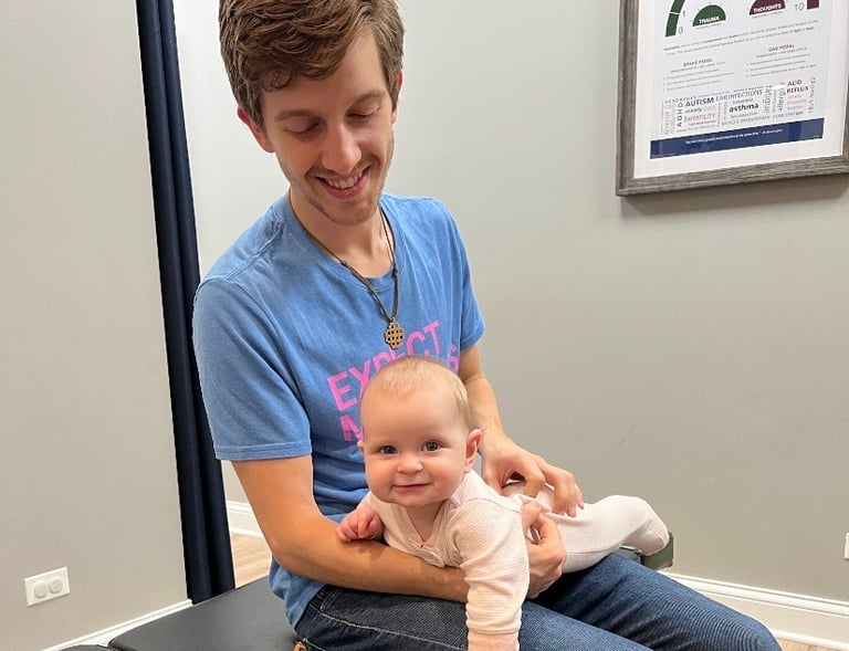 Joyful baby receiving gentle chiropractic care for sleep and digestion