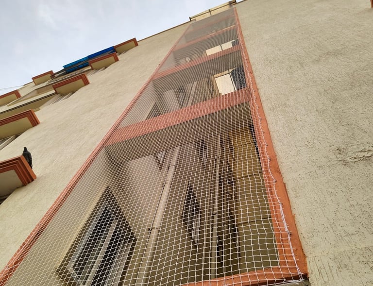 Technician carefully fastening a pigeon net with durable cables along a rooftop duct.