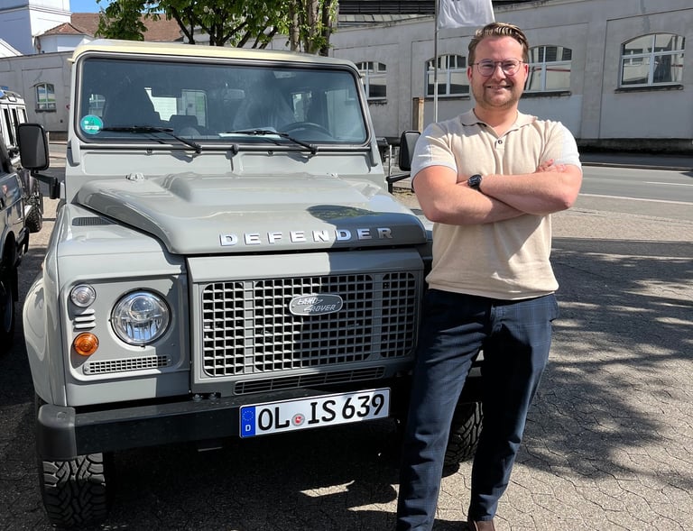  Marcel Serré, organisator van ROUTES oldtimer rally, naast een klassieke Land Rover Defender