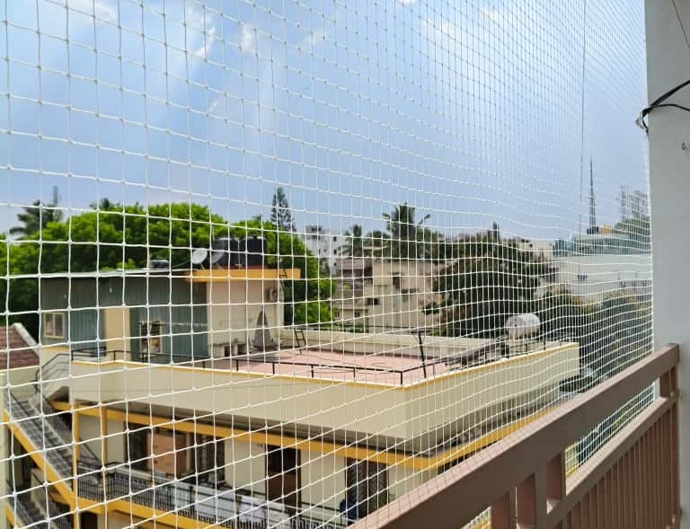 Wide shot showing a pet safely playing behind a protective net on a balcony.