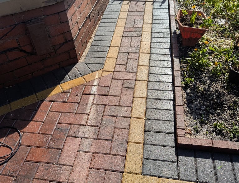 After Red and charcoal block paving front with yellow decorative borders next to a garden bed.