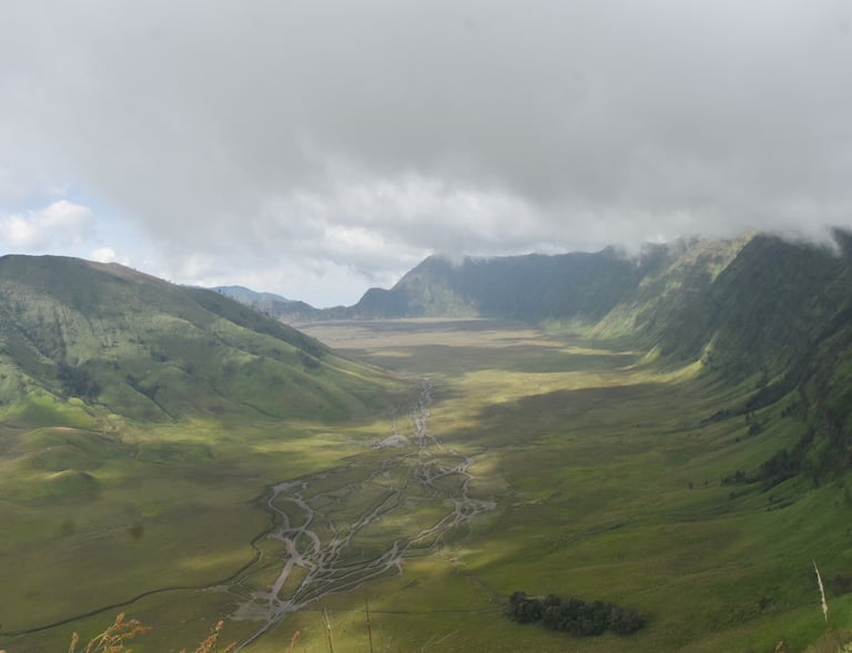 A photographer takes pictures of the green valley, the road leading to Mount Bromo