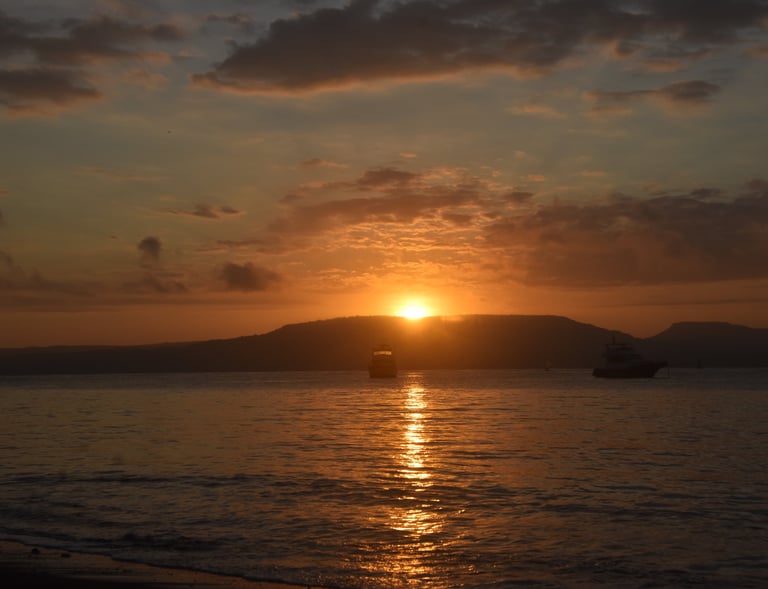 A photographer photographs the sunrise over the Bali Strait. with an orange sky background