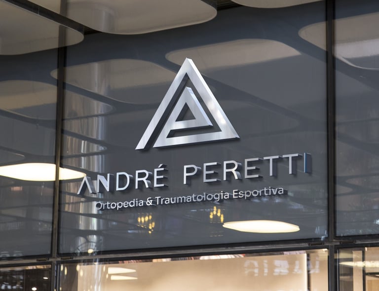 Fachada com logotipo metálico, triângulos e nome “André Peretti” sobre especialidade ortopédica.