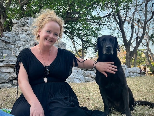 Sunni Dawson smiling with a black Labrador during animal communication session