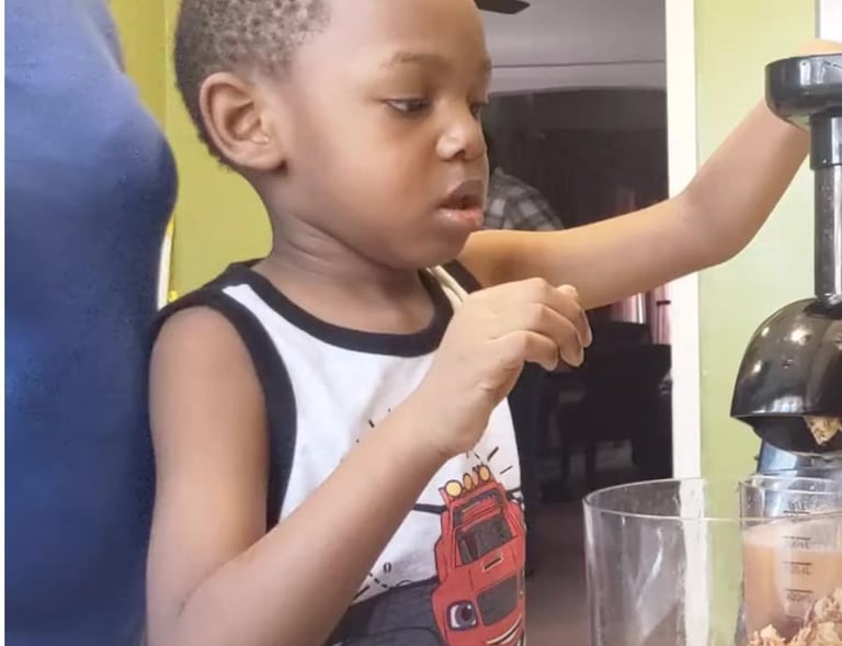 Child juicing fruit with patent supervising.