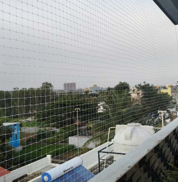 Evening view of a Koramangala balcony with safety netting softly lit by ambient lights.
