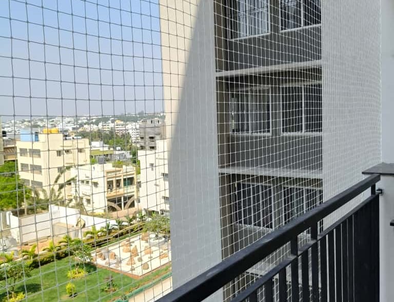Installation team from Junia Safety Nets fitting a safety net on a balcony railing.